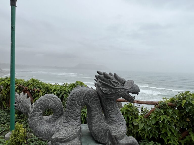 Stone dragon sculpture overlooking the Pacific Ocean at Parque Chino in Miraflores, Lima, Peru, shrouded in coastal mist